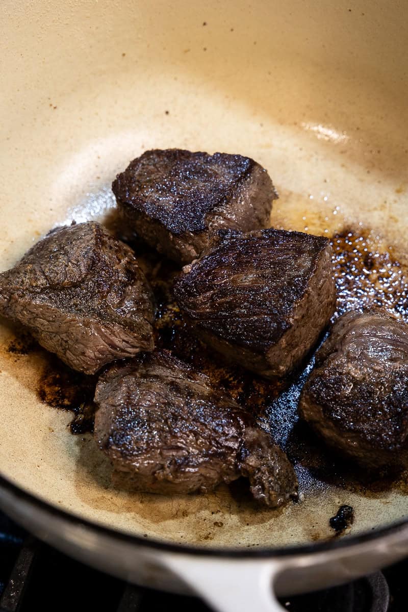 Chunks of seared venison roast in a dutch oven.