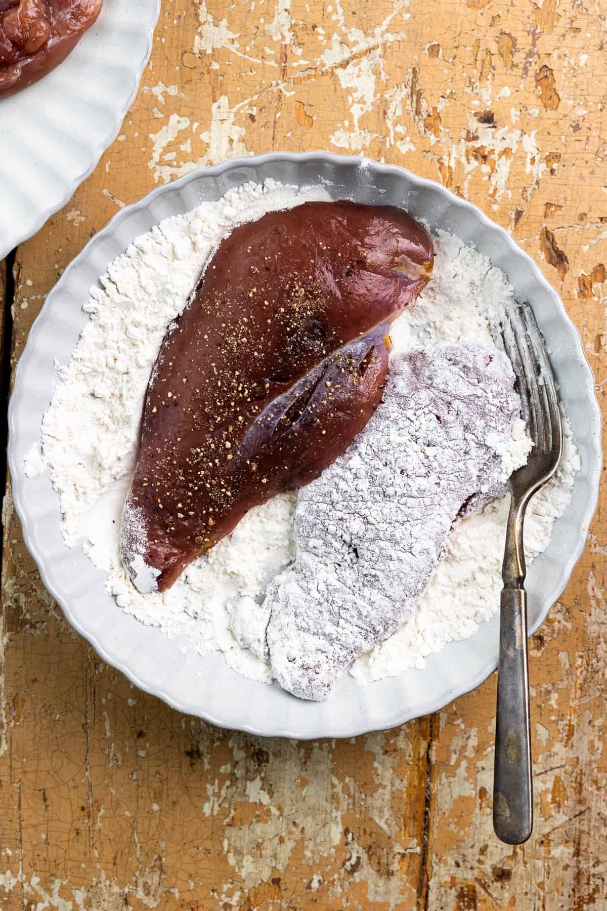 Dredging pheasant breasts in a bowl of flour.
