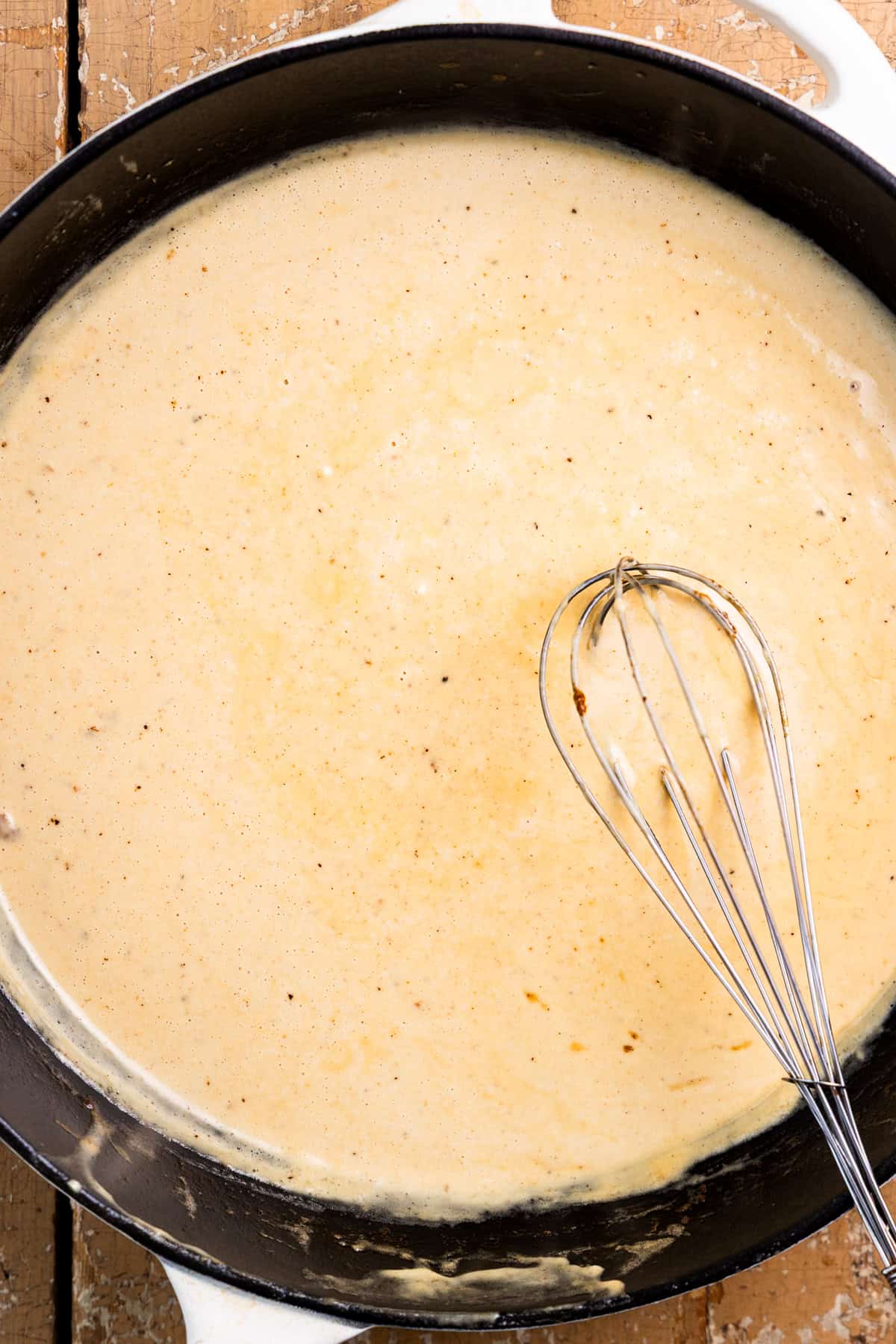 Creamy dijon mustard sauce in a skillet with a whisk.