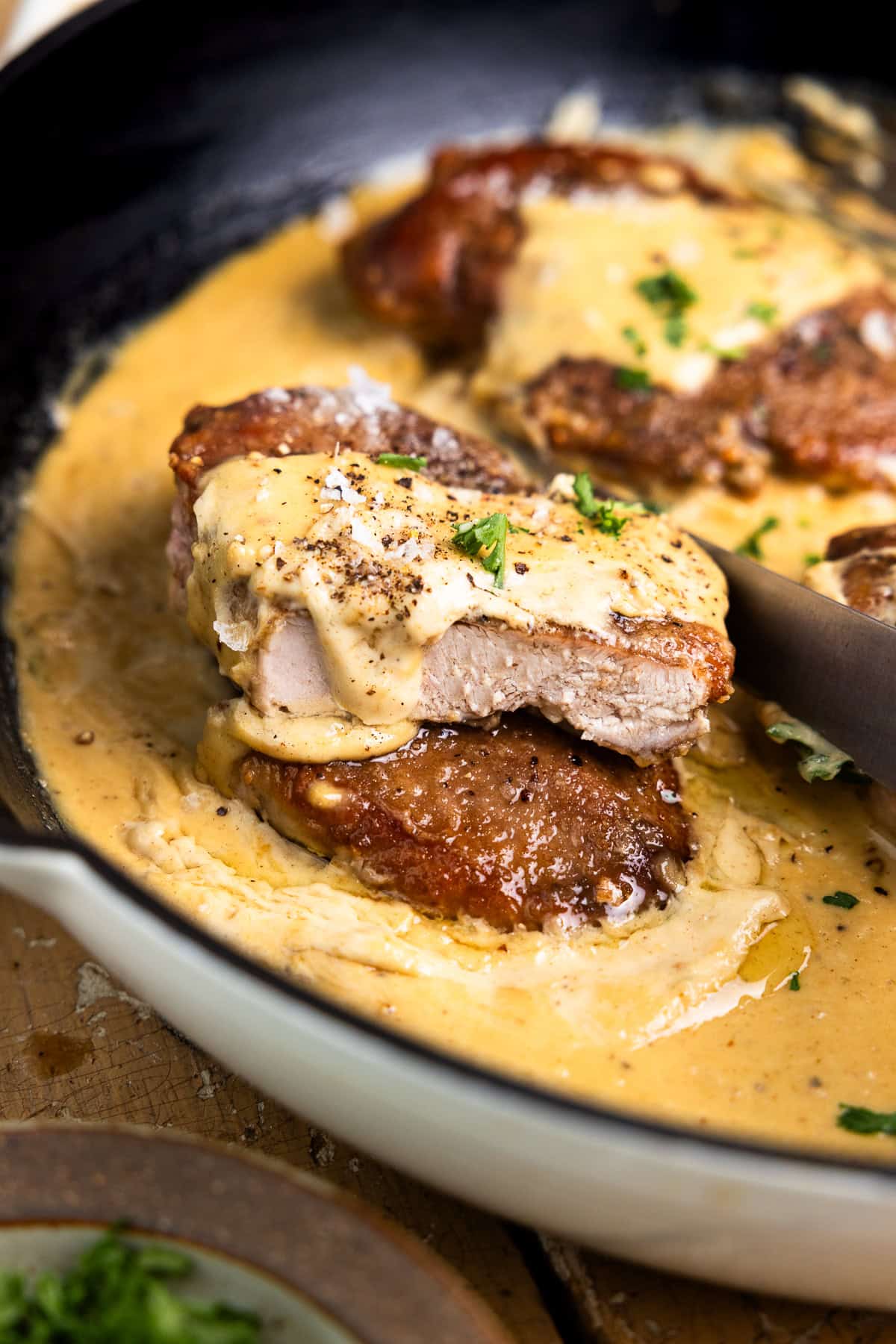 Pheasant breast cut in half in a skillet and drizzled with creamy dijon sauce.