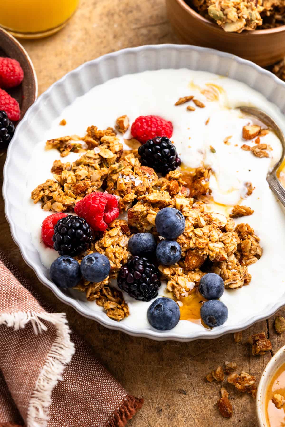 Yogurt in a bowl topped with granola, honey, and fresh berries.