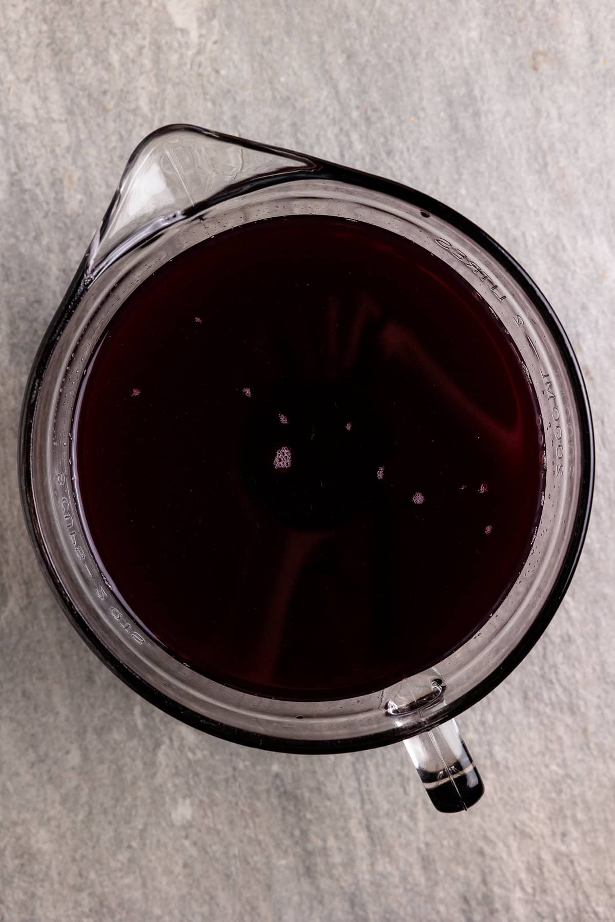 Whey and grape juice mixed together in a measuring bowl.