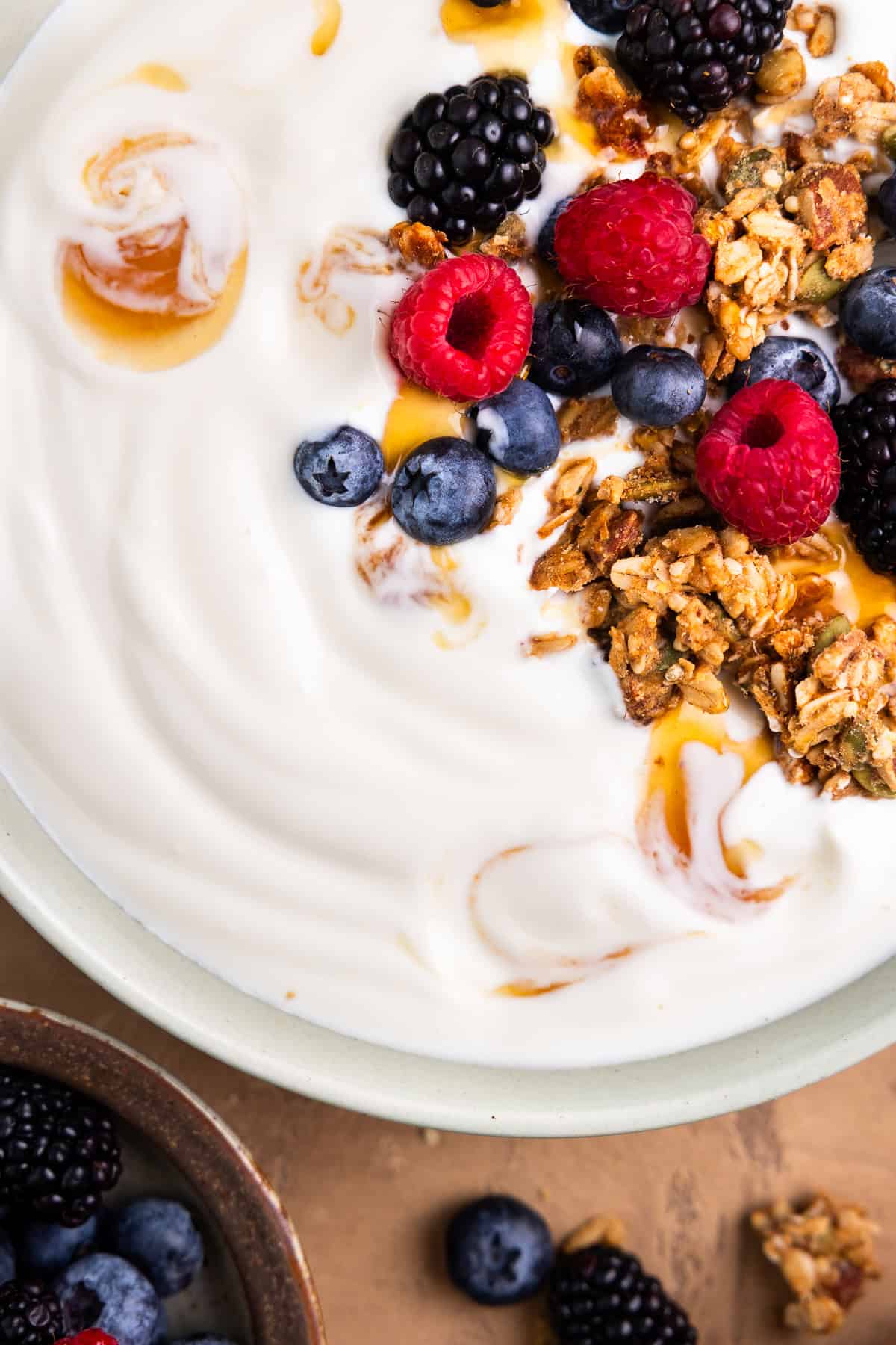 Yogurt in a bowl topped with granola, berries and honey.
