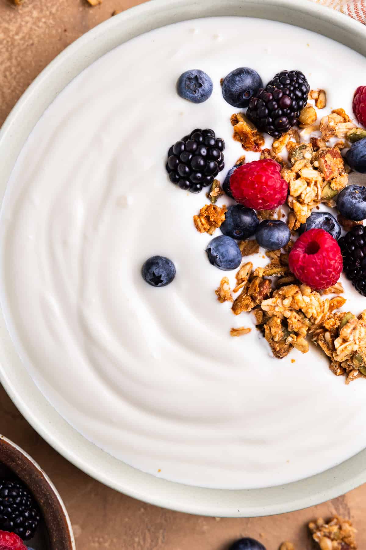 Yogurt in a bowl topped with granola and berries.