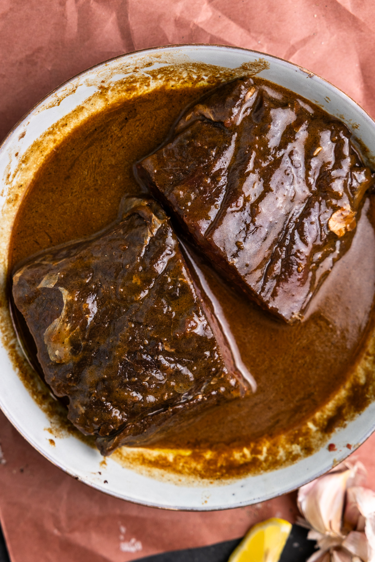 Two venison steaks in a bowl with marinade.