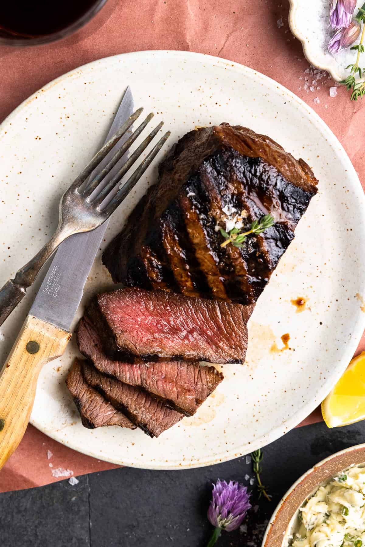 Sliced venison steak on a plate and finished with fresh thyme and flake salt.