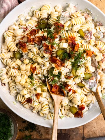Creamy dill pickle pasta salad in a bowl and garnished with fresh dill and bacon.