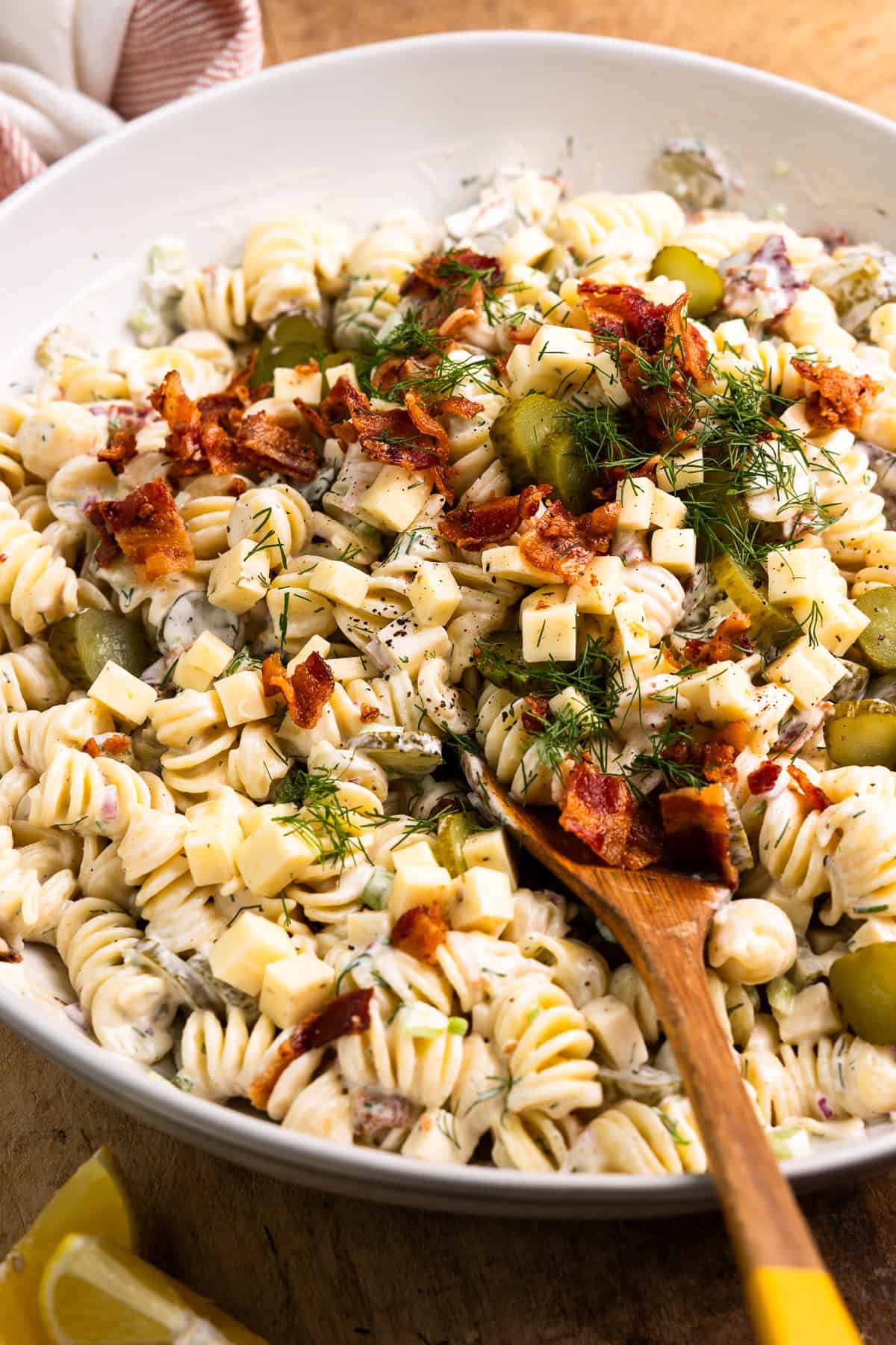 Scooping dill pickle pasta salad from a bowl.