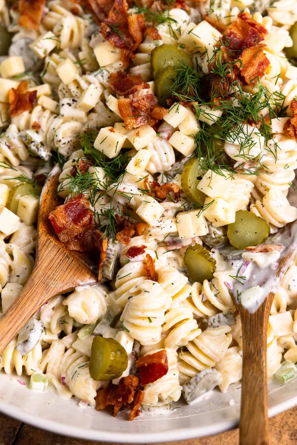Dill pickle pasta salad mixed together in a bowl with a spoon.